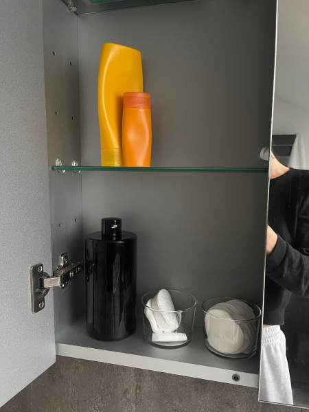 inside a bathroom cabinet with beauty products with no labels sitting on shelves